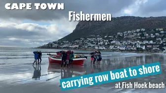 Cape Town Fishermen carrying row boat to shore at Fish Hoek beach