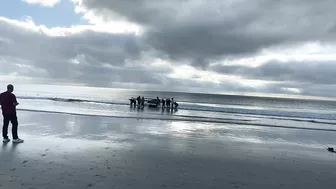 Cape Town Fishermen carrying row boat to shore at Fish Hoek beach