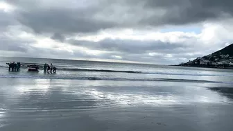 Cape Town Fishermen carrying row boat to shore at Fish Hoek beach