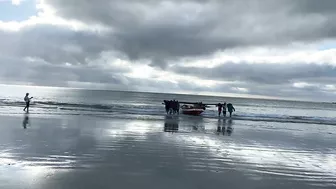 Cape Town Fishermen carrying row boat to shore at Fish Hoek beach