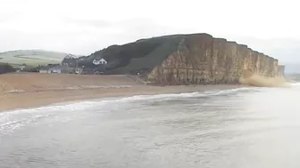 Moment massive chunk of West Bay cliff falls onto beach