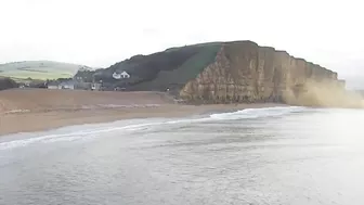 Moment massive chunk of West Bay cliff falls onto beach