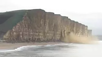 Moment massive chunk of West Bay cliff falls onto beach